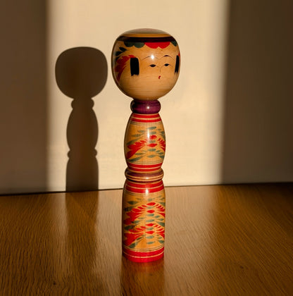 Kokeshi Yajiro en bois peint par Sato Naoki, artisan japonais, éclairée par la lumière du soleil, style traditionnel du Tōhoku.