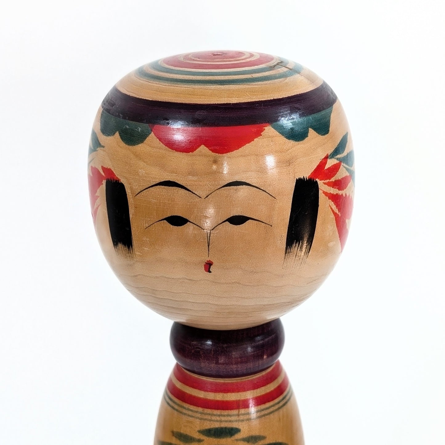 Détail du visage de la Kokeshi Yajiro artisanale par Sato Naoki, avec motifs peints à la main et expression douce.