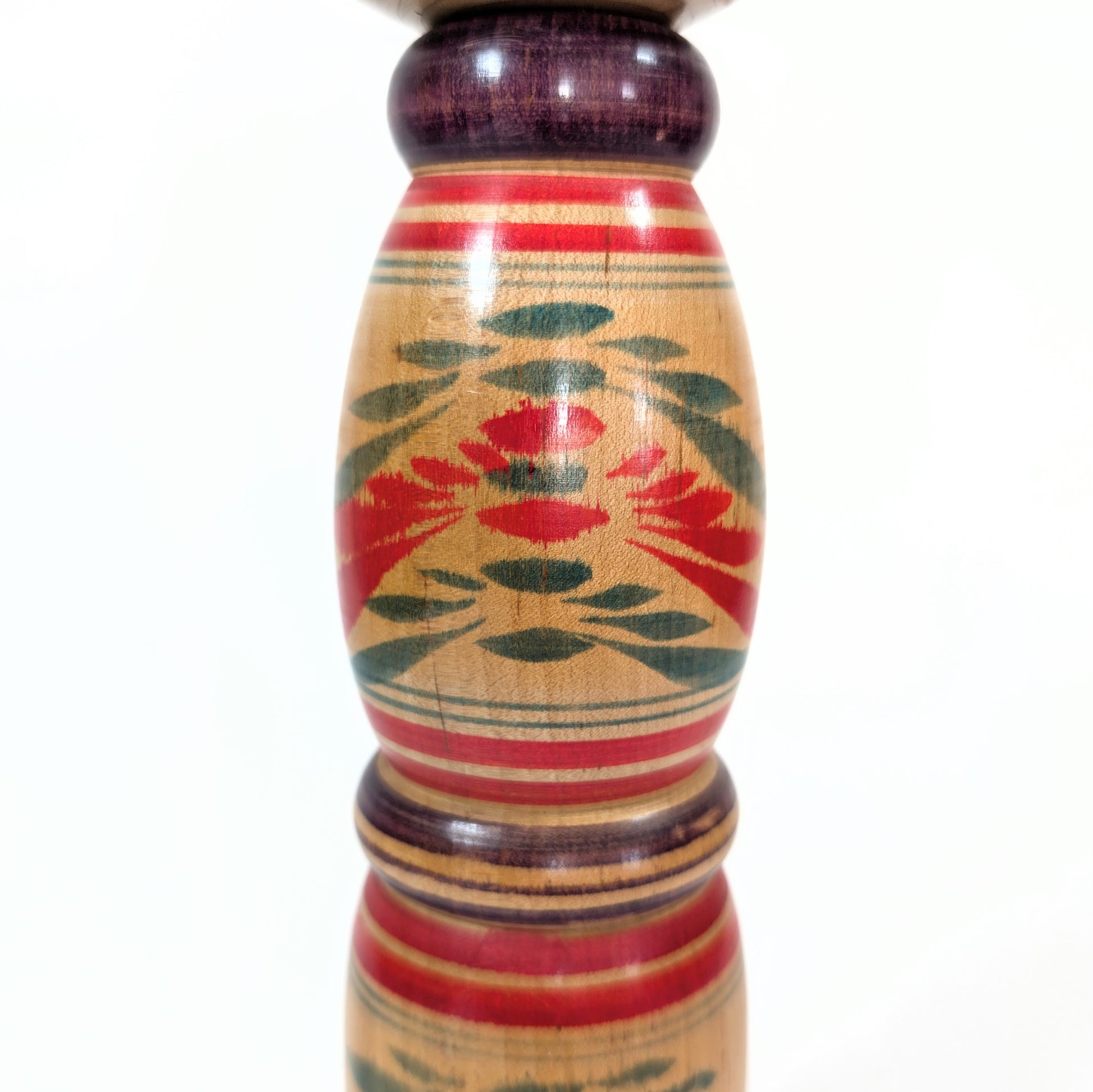 Détail du corps d’une Kokeshi Yajiro de Sato Naoki, présentant un motif floral stylisé peint à la main, typique de l’époque Showa.