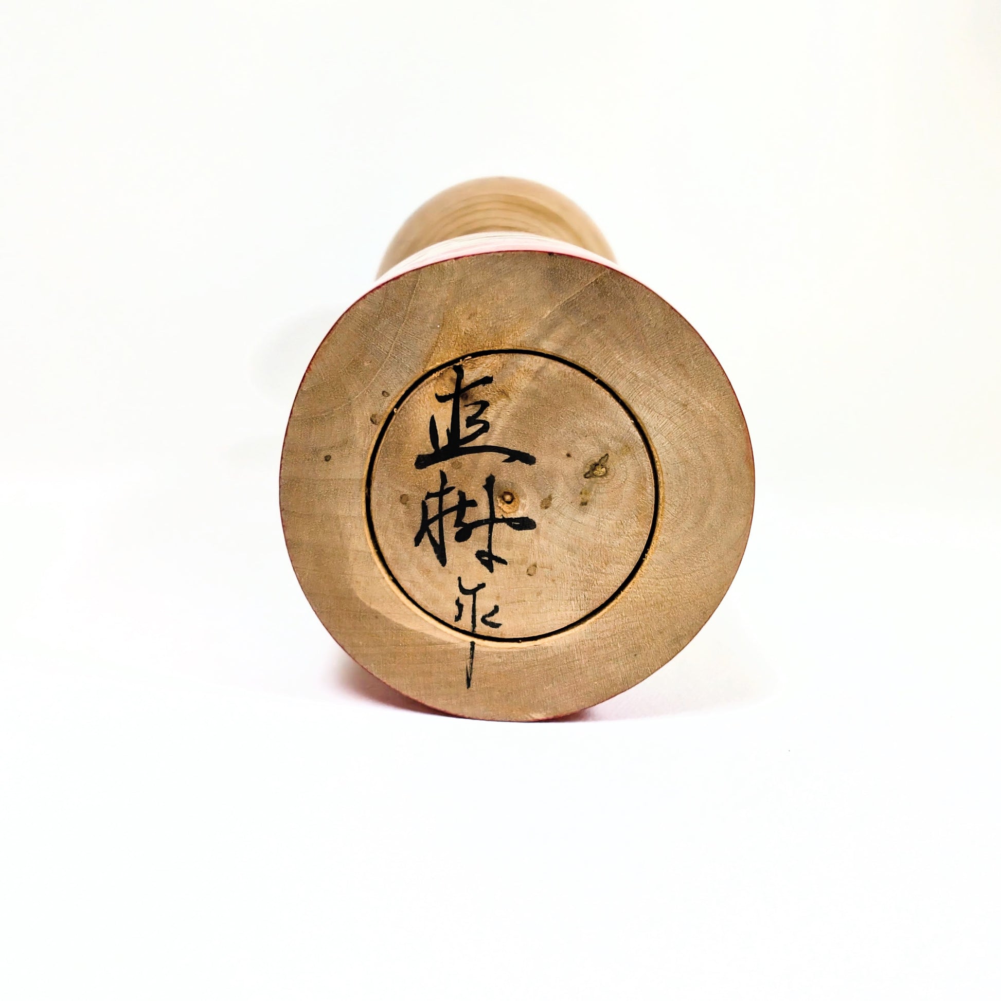 Signature de l’artisan japonais Sato Naoki sous une kokeshi Yajiro, poupée traditionnelle en bois fabriquée à la main.