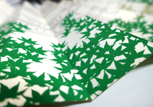 Gros plan sur les feuilles d’érable vert aomomiji d’un éventail japonais traditionnel en papier nacré.