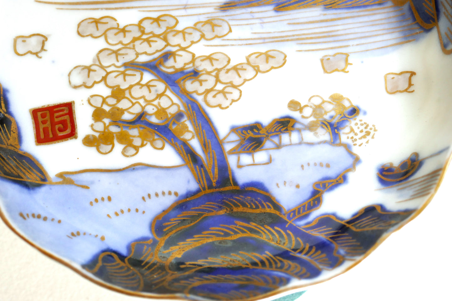 Détail du décor peint main au bas de l’assiette : racines, cerisier, toiture japonaise et paysage stylisé