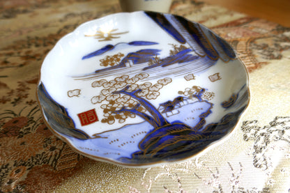 Gros plan sur le décor doré de paysage japonais et le sceau rouge Hizen sur assiette Meiji