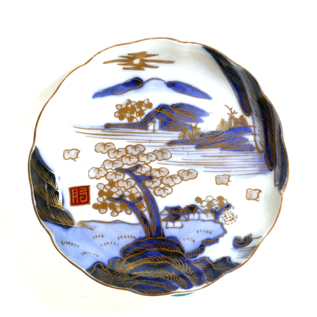 Vue de face d’une assiette Arita Meiji, paysage de montagne avec sakura et oiseaux, en bleu cobalt et or