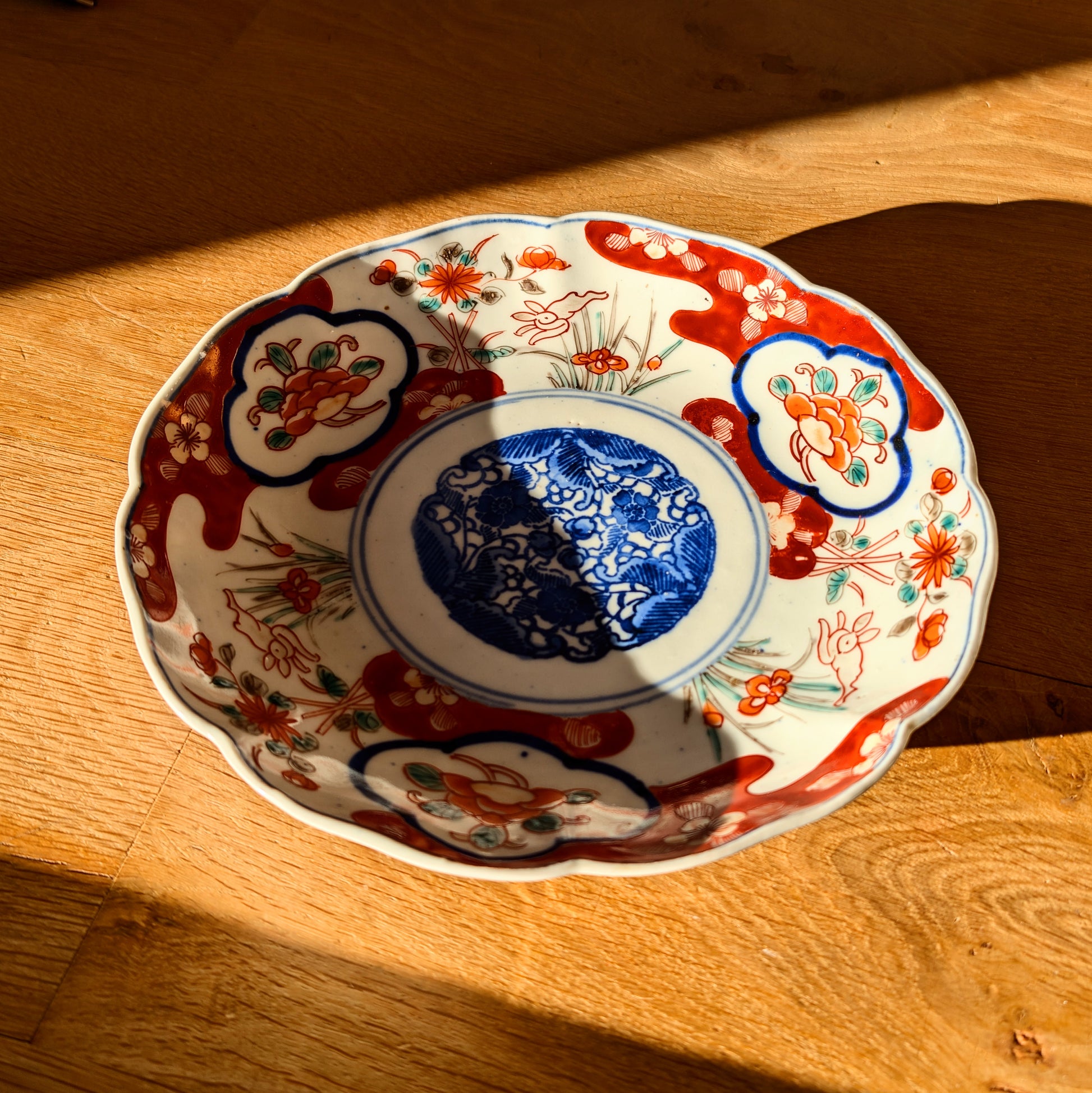 Assiette Imari antiquité japonaise en lumière naturelle, porcelaine Arita avec décor floral et scène kacho-ga