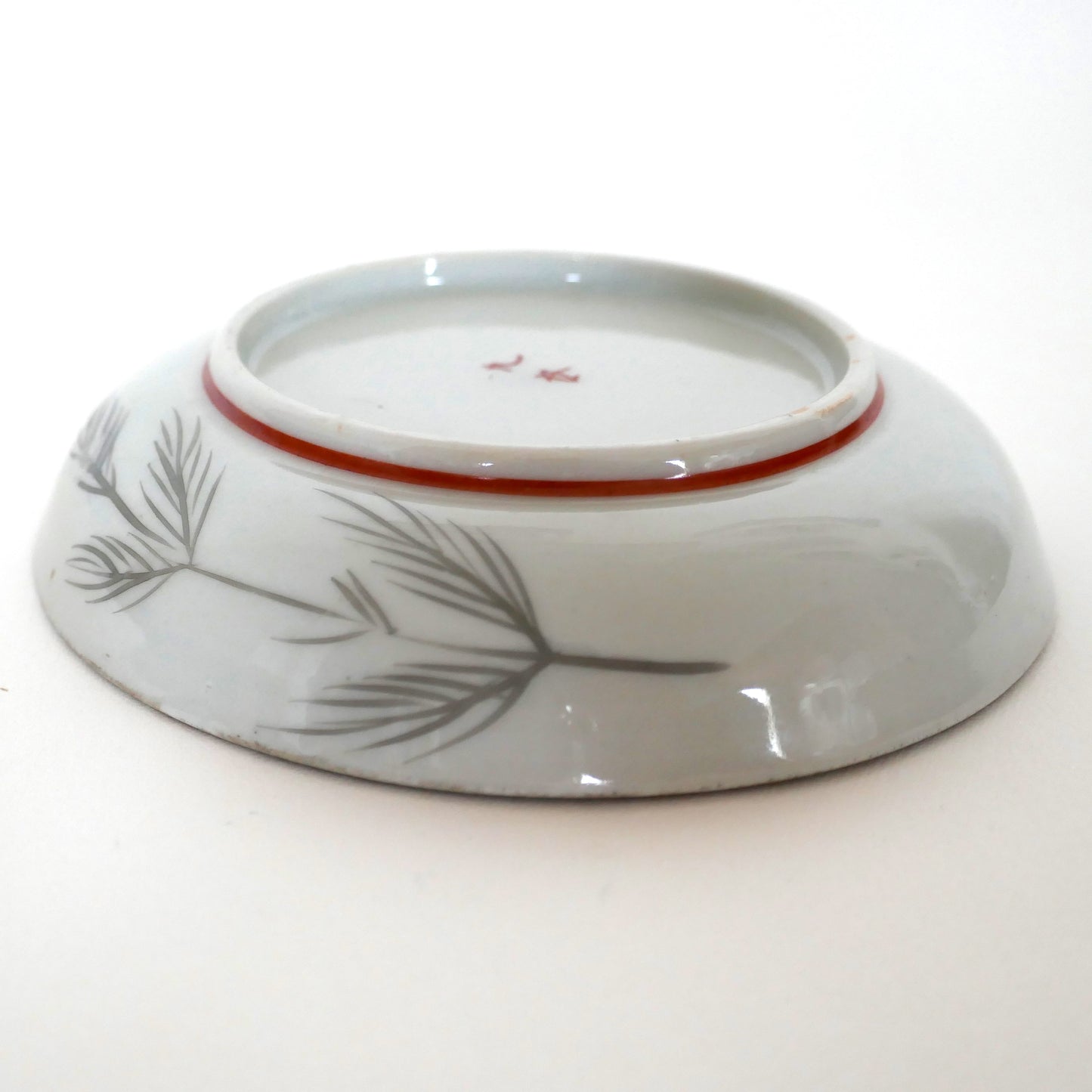 Assiette japonaise Kutani vue de profil, décor de pins stylisés au revers