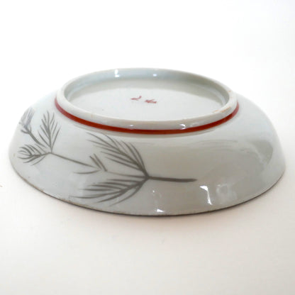 Assiette japonaise Kutani vue de profil, décor de pins stylisés au revers