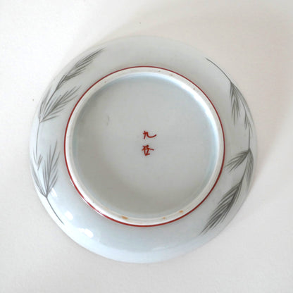 Vue du dessous de l’assiette Kutani avec signature 九谷 et décor de branches de pin
