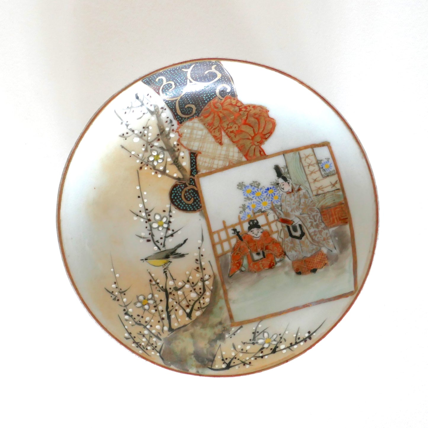 Vue complète d’une assiette japonaise Kutani avec décor peint à la main : scène de cour, fleurs et oiseau