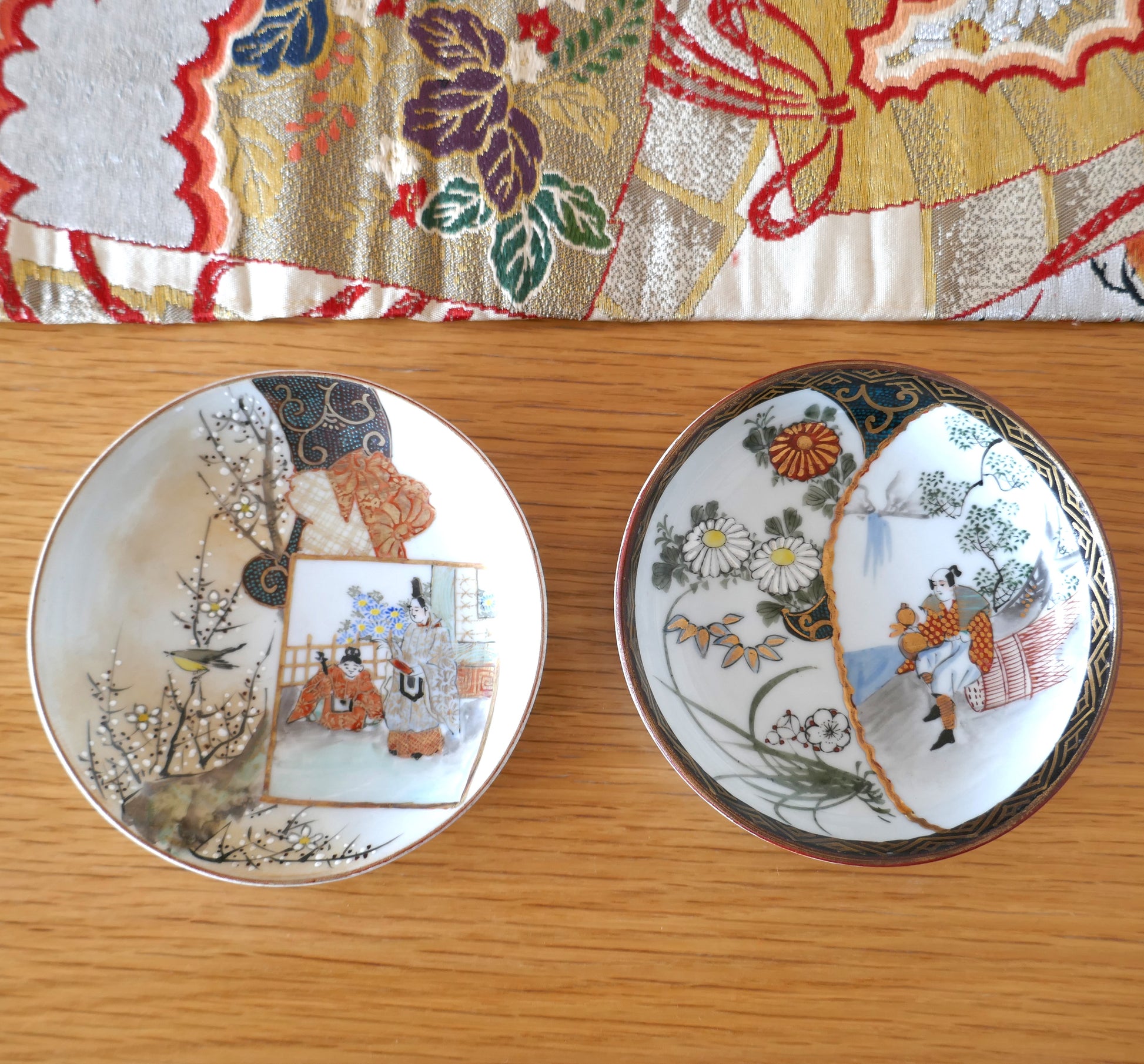 Deux assiettes anciennes Kutani côte à côte sur fond de tissu japonais coloré