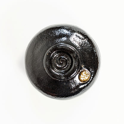 Base du bol japonais fait main avec pied spiralé et sceau 光楽 de Watanabe Kōraku dans la glaçure noire.

