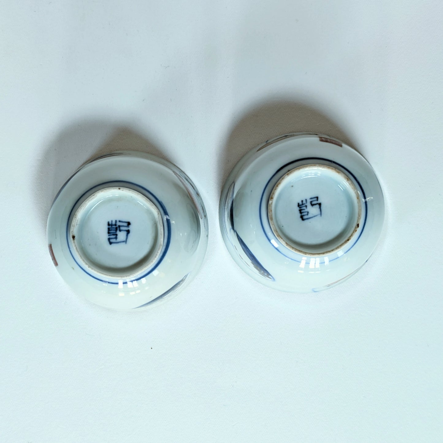 Dessous de deux guinomi en porcelaine Arita montrant la marque Ken 兼, production Hizen période Edo tardif.