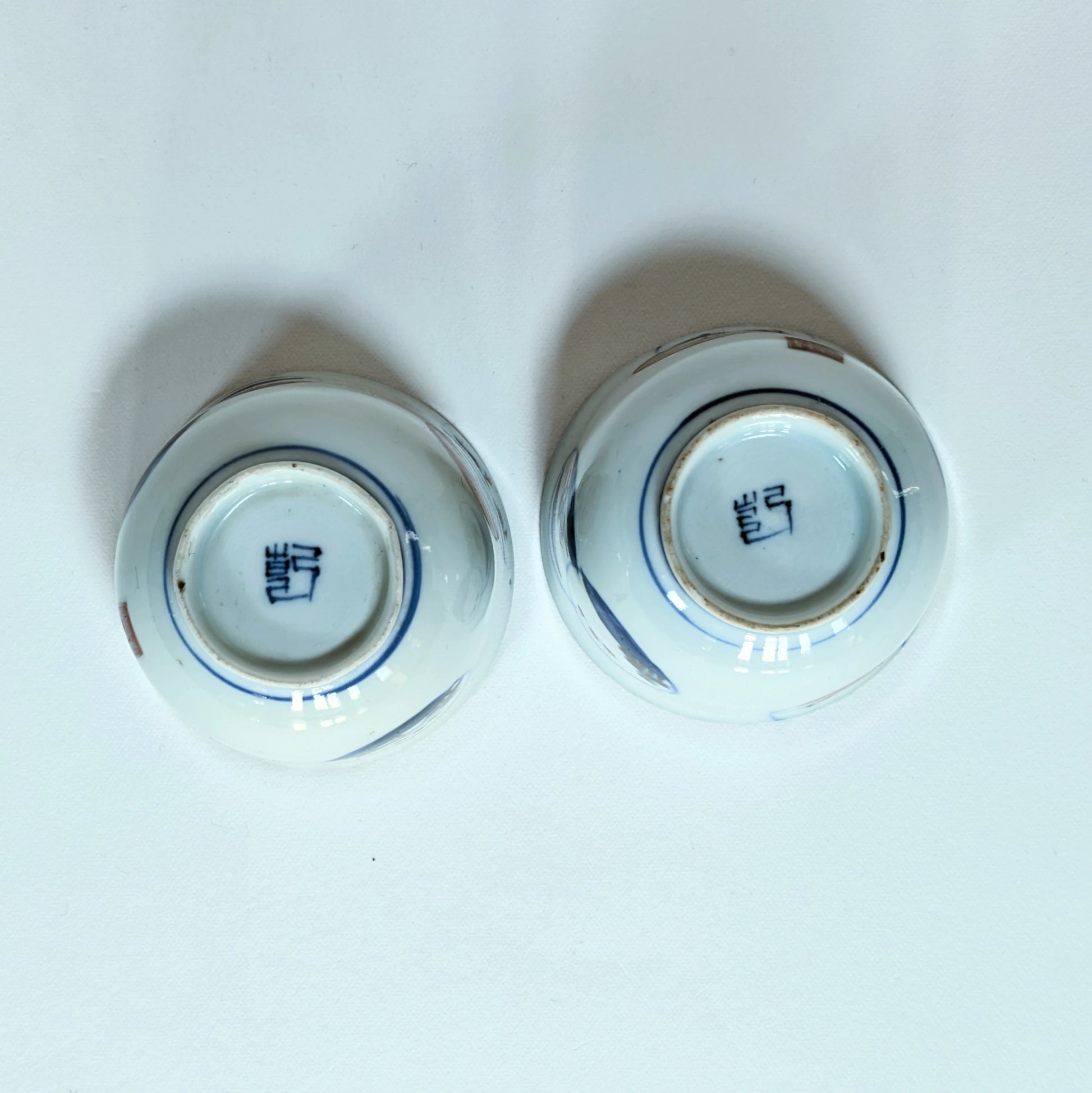 Dessous de deux guinomi en porcelaine Arita montrant la marque Ken 兼, production Hizen période Edo tardif.