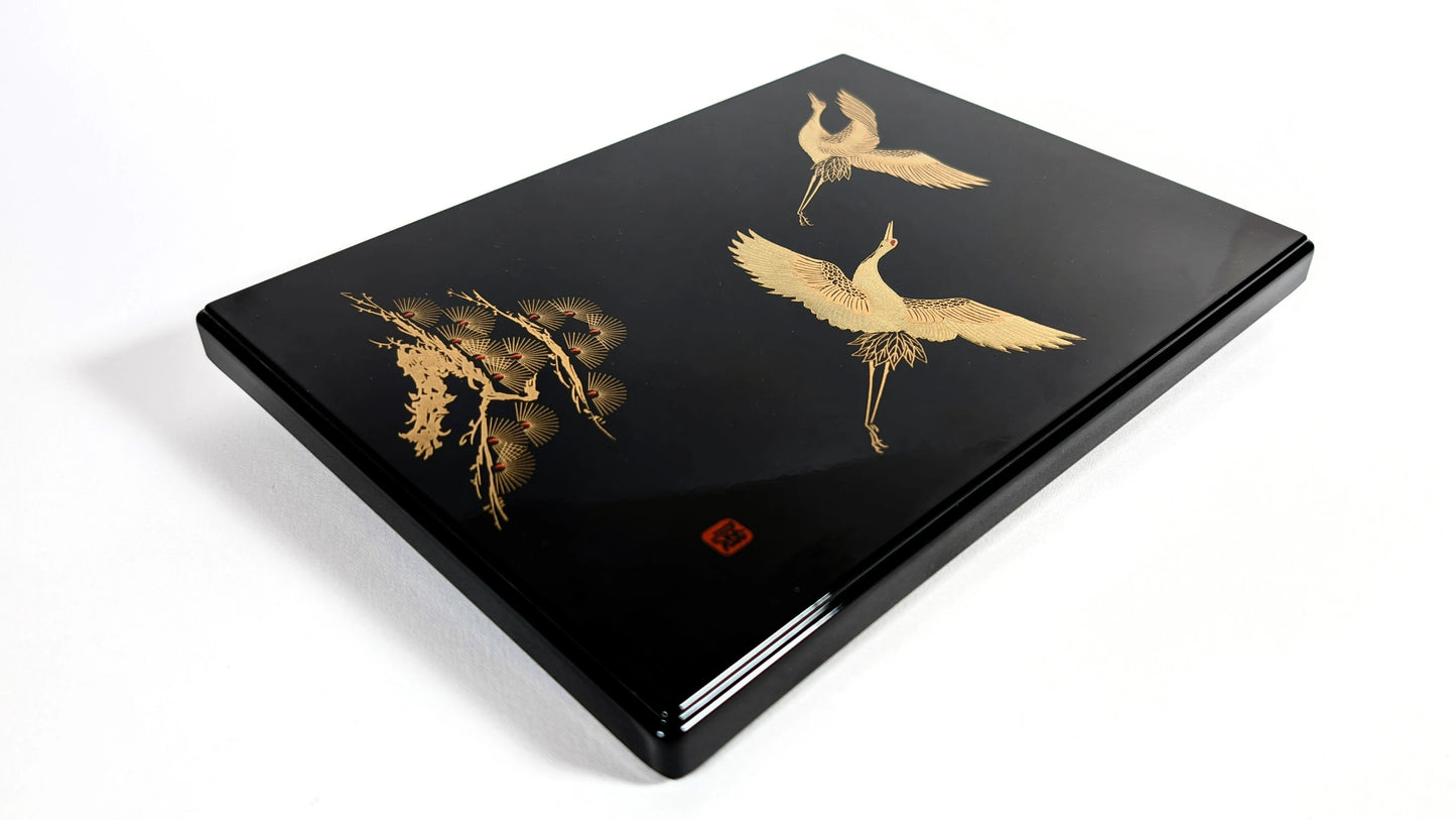 Boîte en laque japonaise noire, décor maki-e de grues et pin stylisé, vue trois-quarts.