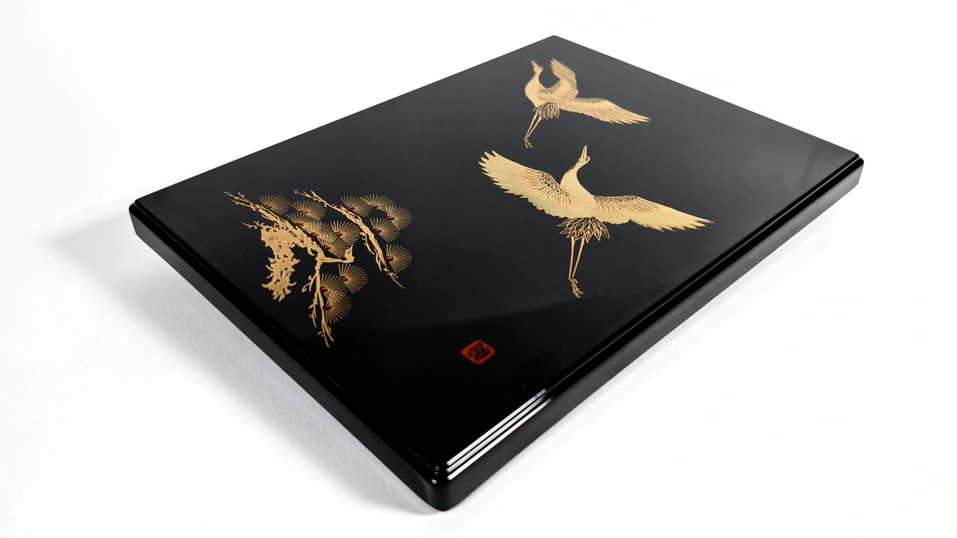 Boîte en laque japonaise noire, décor maki-e de grues et pin stylisé, vue trois-quarts.