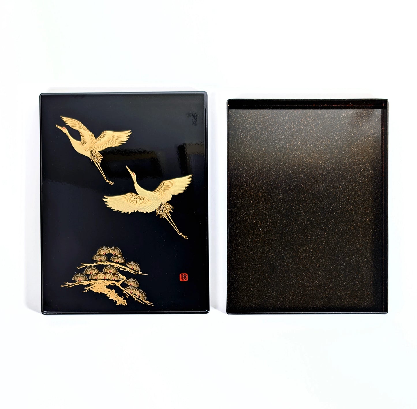 Boîte japonaise en laque noire présentée ouverte, décor de grues dorées sur le couvercle et intérieur nashiji.