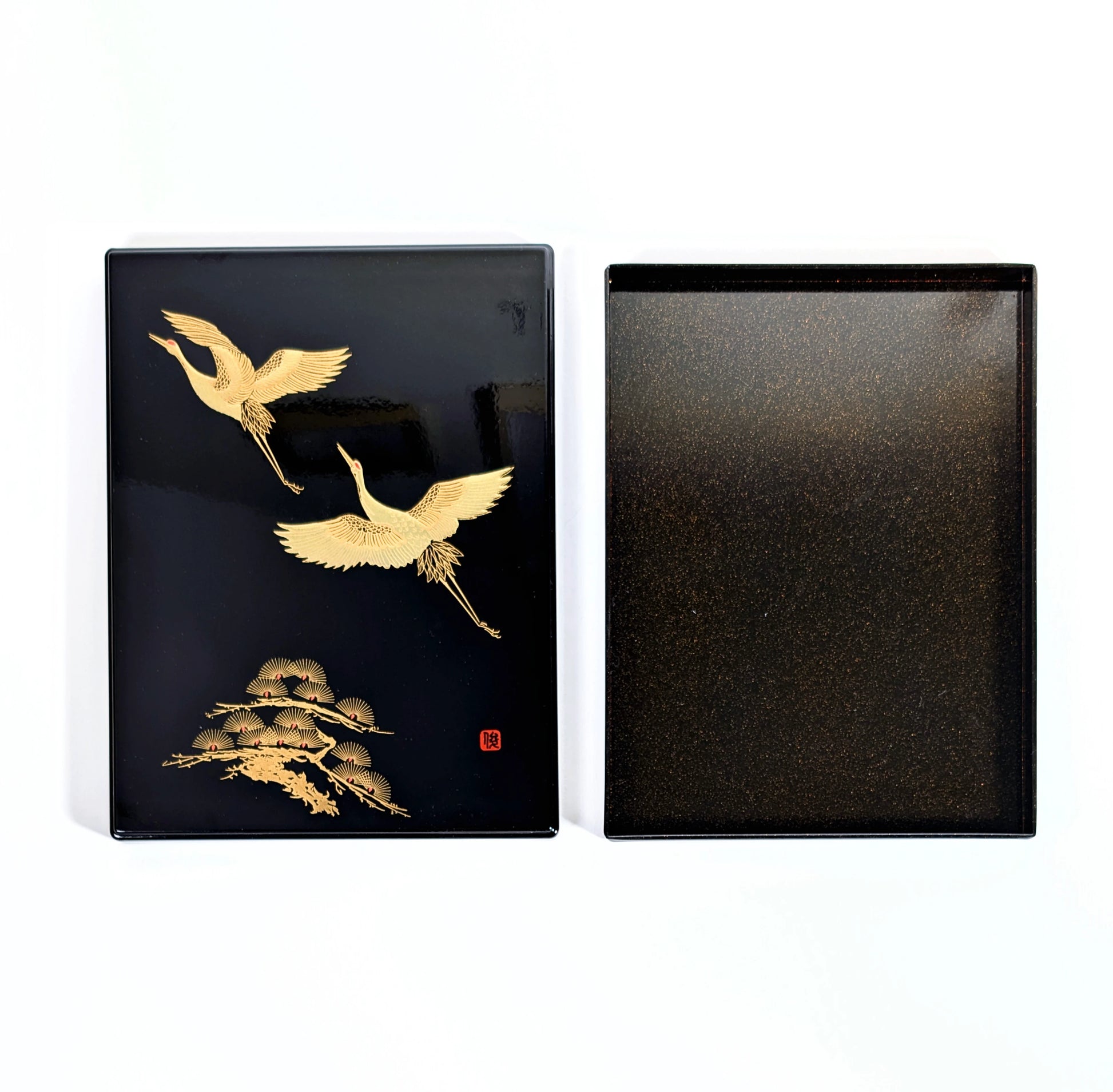 Boîte japonaise en laque noire présentée ouverte, décor de grues dorées sur le couvercle et intérieur nashiji.