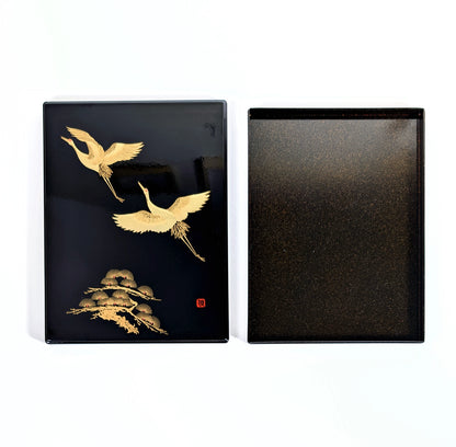 Boîte japonaise en laque noire présentée ouverte, décor de grues dorées sur le couvercle et intérieur nashiji.