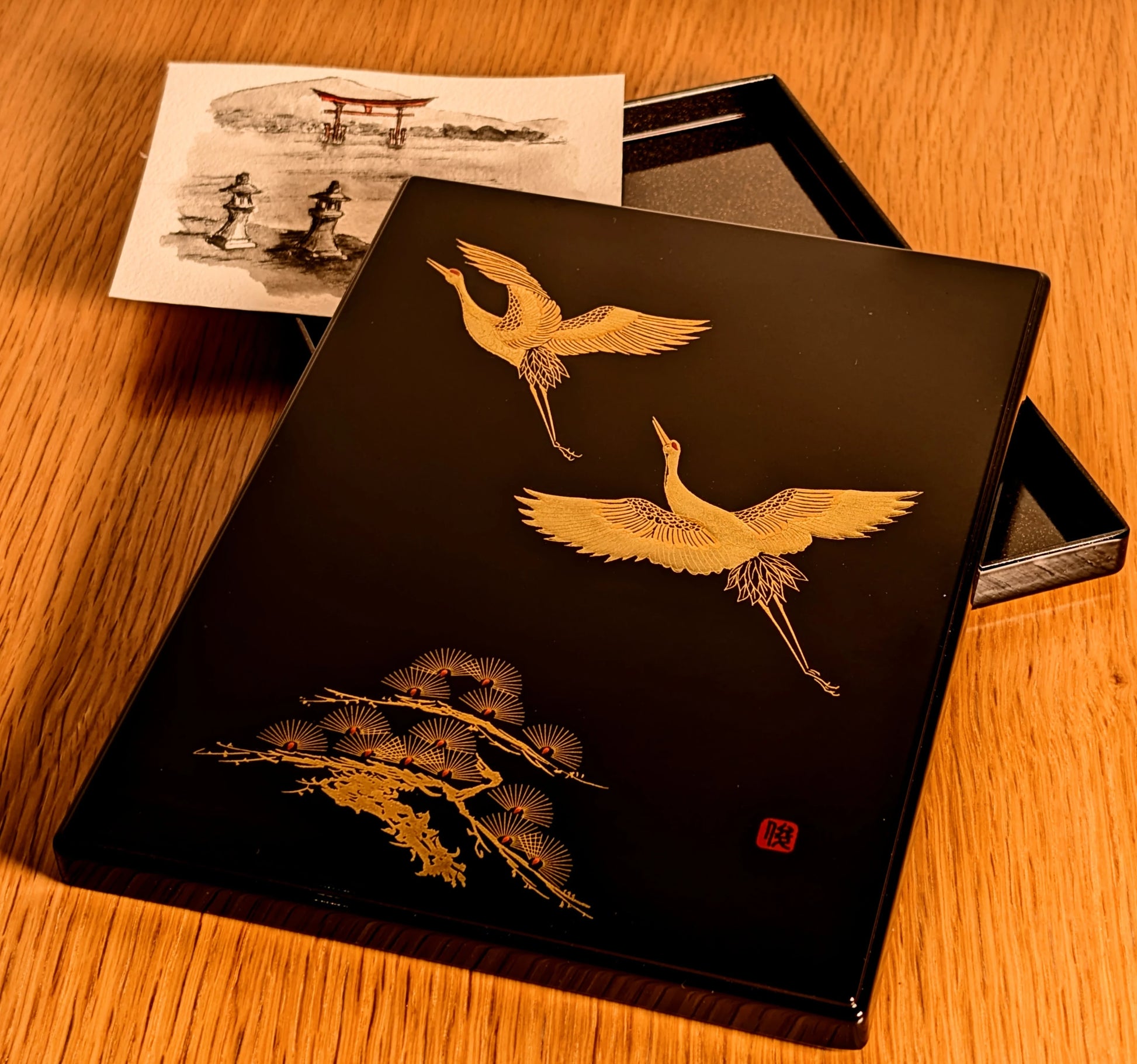 Boîte japonaise en laque noire décorée de grues dorées, utilisée pour conserver lettres ou cartes.