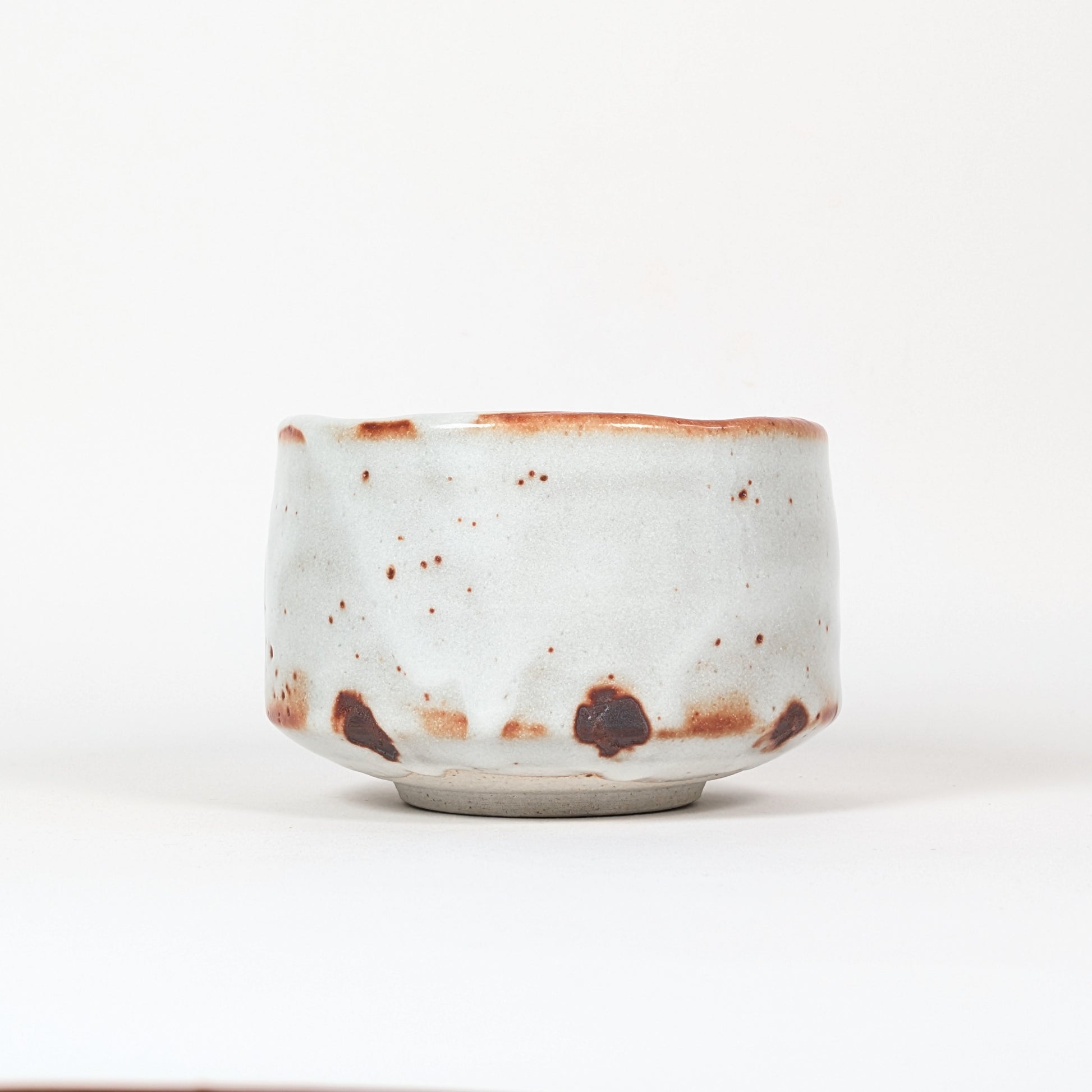 Bol à thé japonais Beni Shino avec émail blanc irrégulier, bord légèrement ondulé et taches de cuisson brun rouille dans l’esprit wabi sabi.