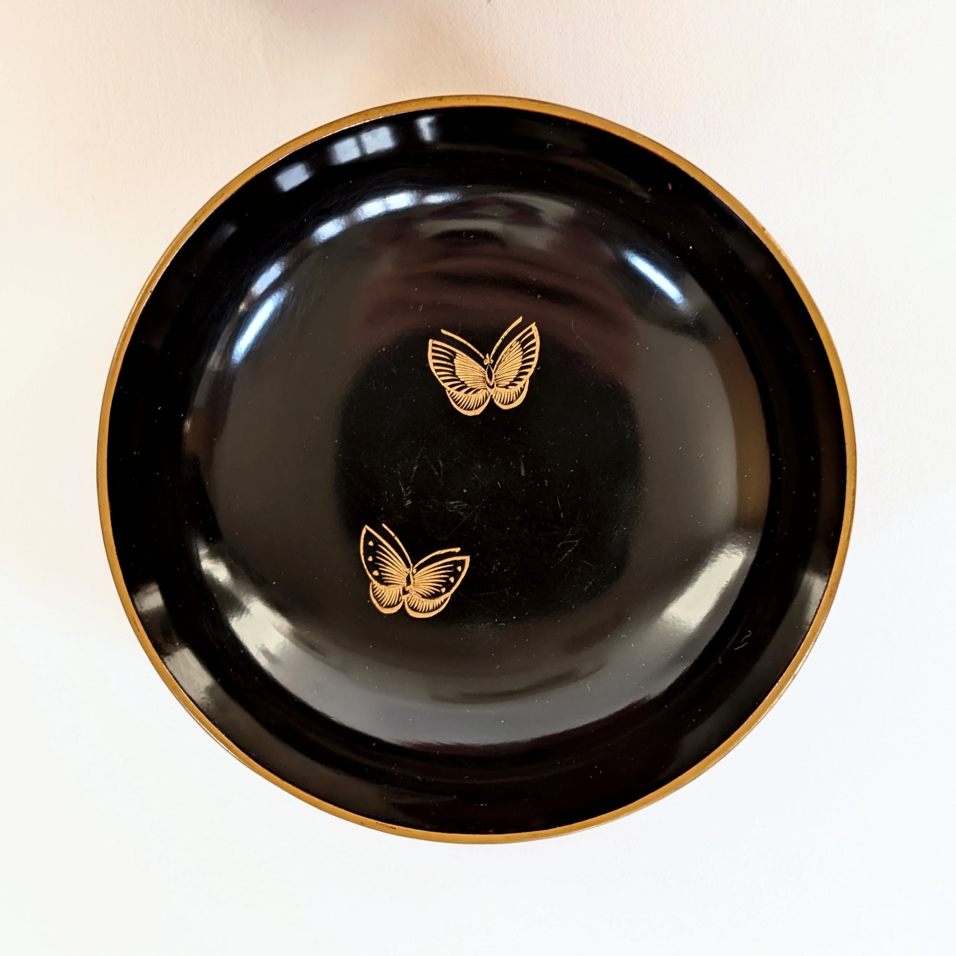 Intérieur noir d’un bol japonais en laque urushi, illustré de deux papillons dorés en maki-e.