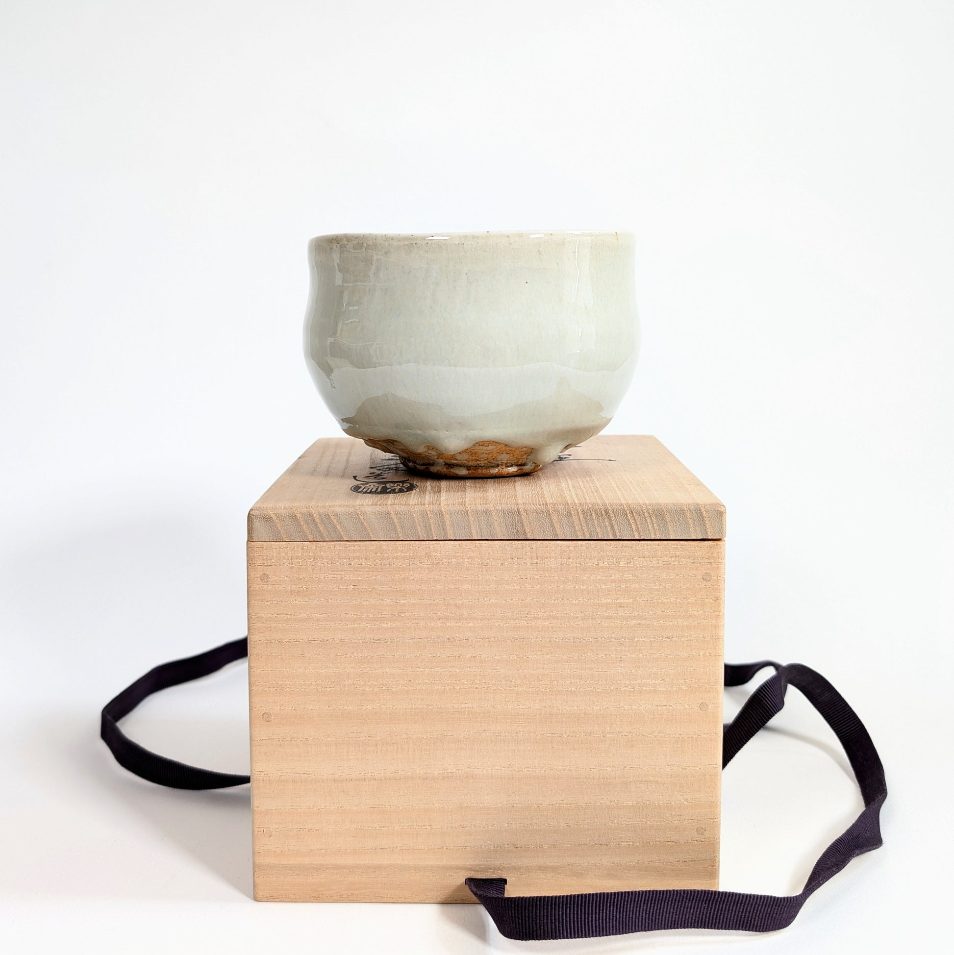 Bol matcha artisanal japonais en céramique Akahada-yaki présenté sur sa boîte en bois signée