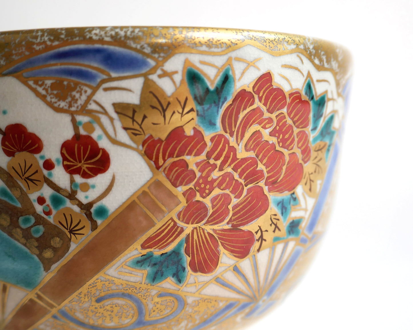 Détail du bol à matcha japonais montrant une pivoine botan rouge, des fleurs de prunier et un éventail rehaussé d’or.