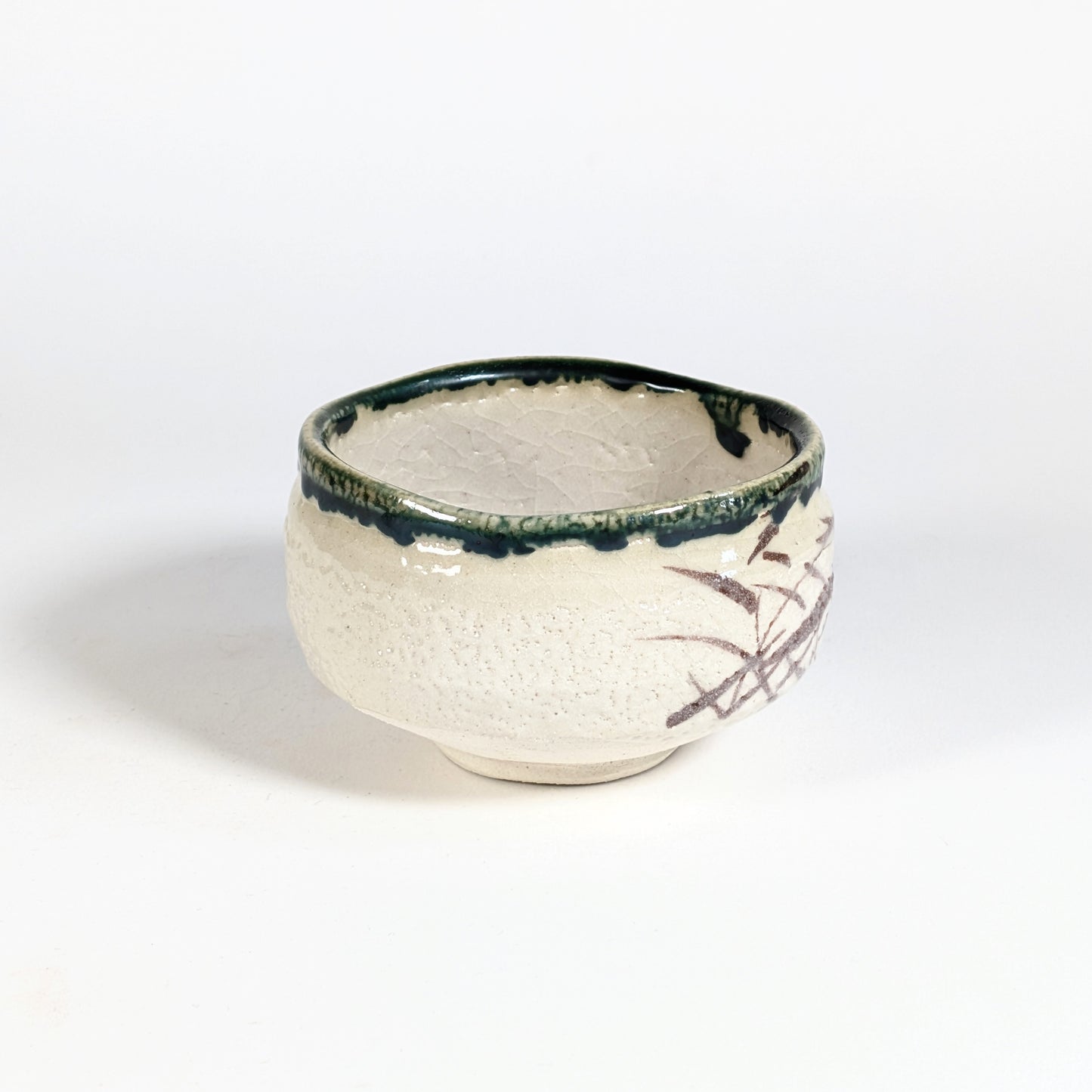Bol matcha Oribe-yaki artisanal avec bord vert profond, émail crème craquelé et décor brun partiel