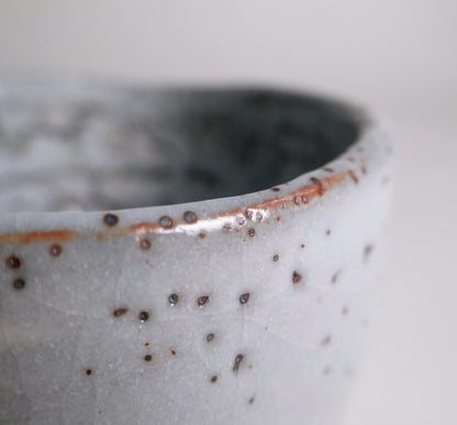 Détail du bord du chawan Shino avec yuzuhada et nuances ferrugineuses hi-iro rouge-orangé produites à la cuisson.