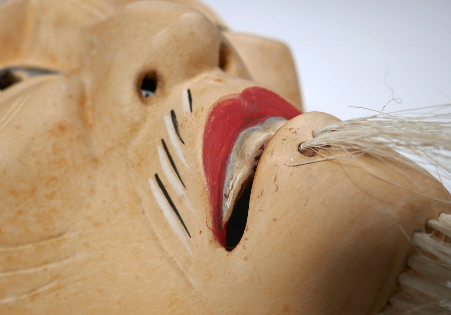 Détail de la bouche peinte et de la barbe en crin naturel d’un masque Nô japonais ancien, fait main selon la tradition.