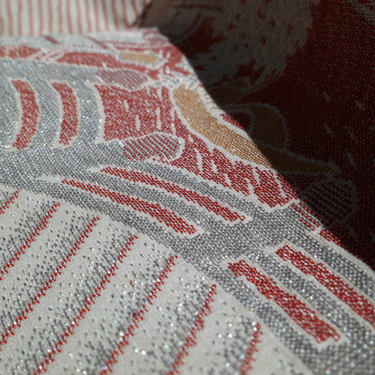 Gros plan du tissage broché du haori japonais en soie, révélant les fils métallisés argentés et les détails colorés du décor