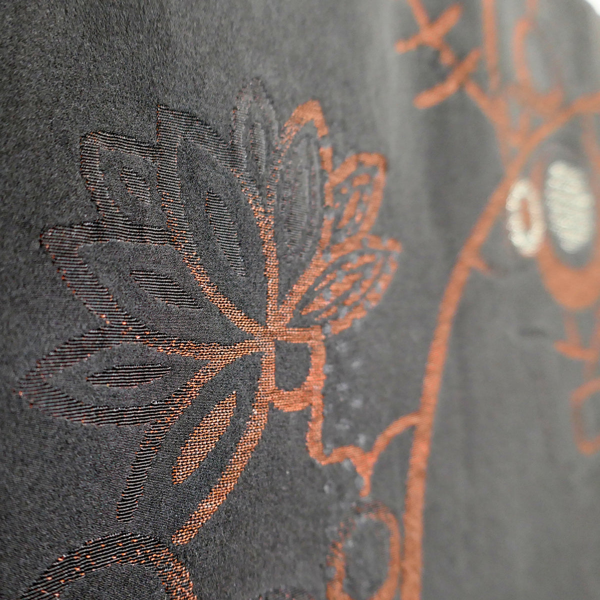 Détail du brocart de soie d'une veste haori japonaise, orné de feuilles stylisées et d'arabesques végétales cuivrées d'inspiration karakusa.