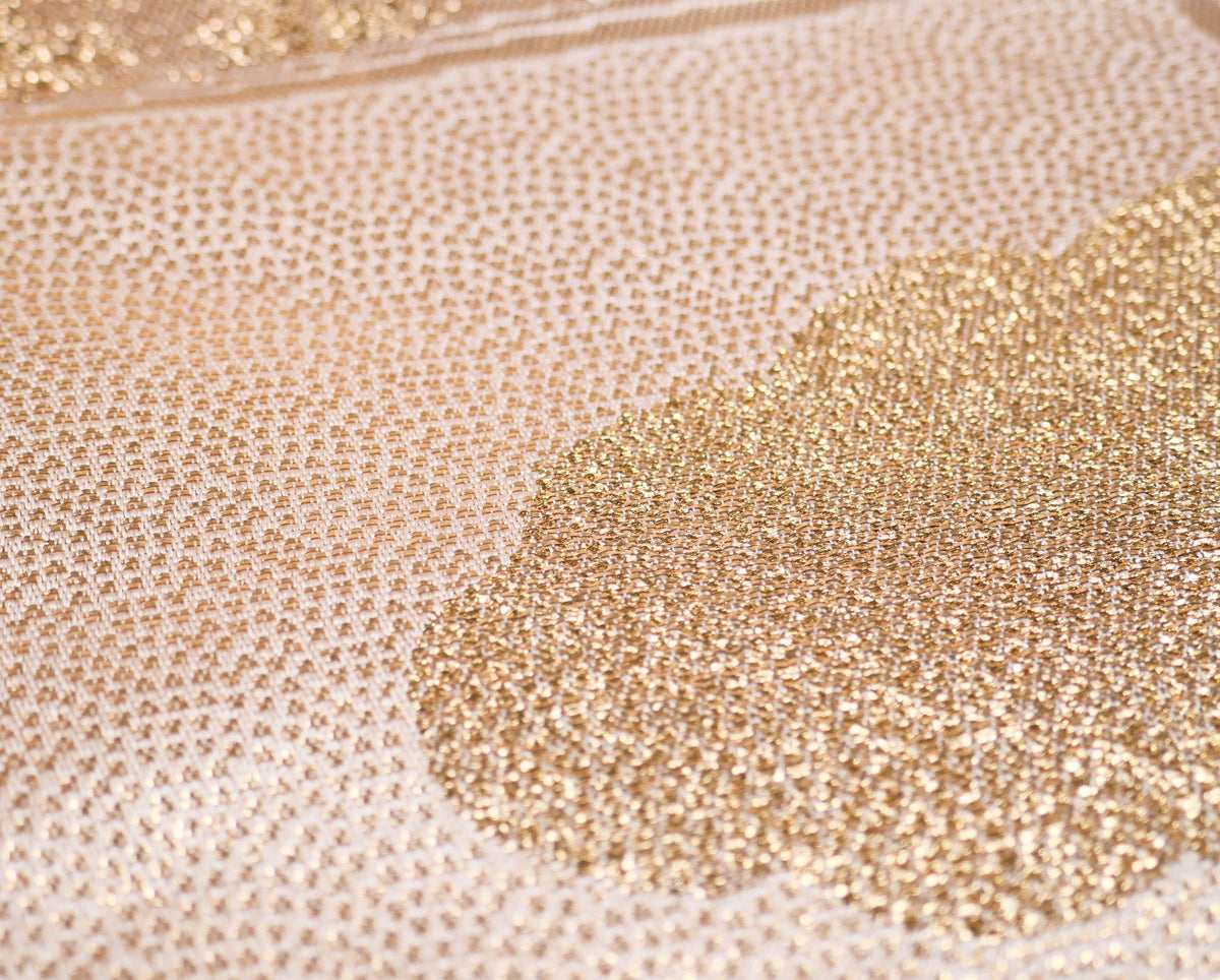 Macro du brocart de soie d’un fukuro obi avec motif samekomon doré sur fond ivoire champagne