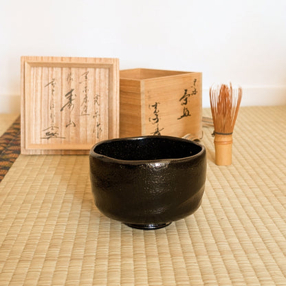 Mise en scène chanoyu sur tatami avec bol matcha noir, chasen en bambou et tomobako en bois de paulownia.
