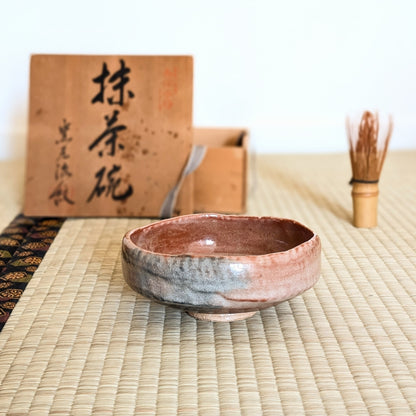 Chawan aka raku rose modèle hirachawan posé sur tatami avec chasen et boîte bois pour cérémonie du thé japonaise