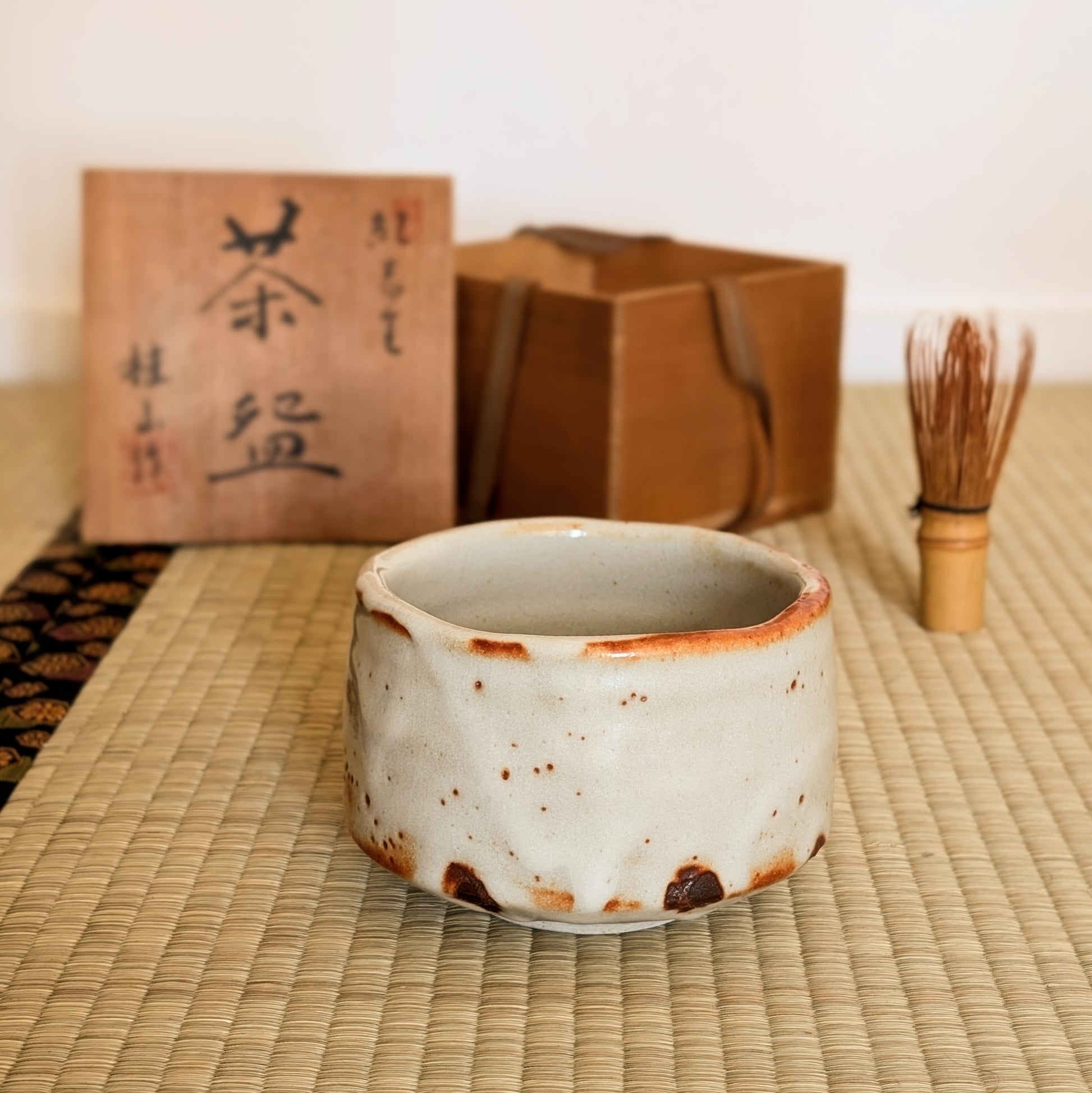 Chawan Beni Shino mis en scène pour la cérémonie du thé japonaise sur tatami, avec tomobako signé, chasen et accessoires de chanoyu.