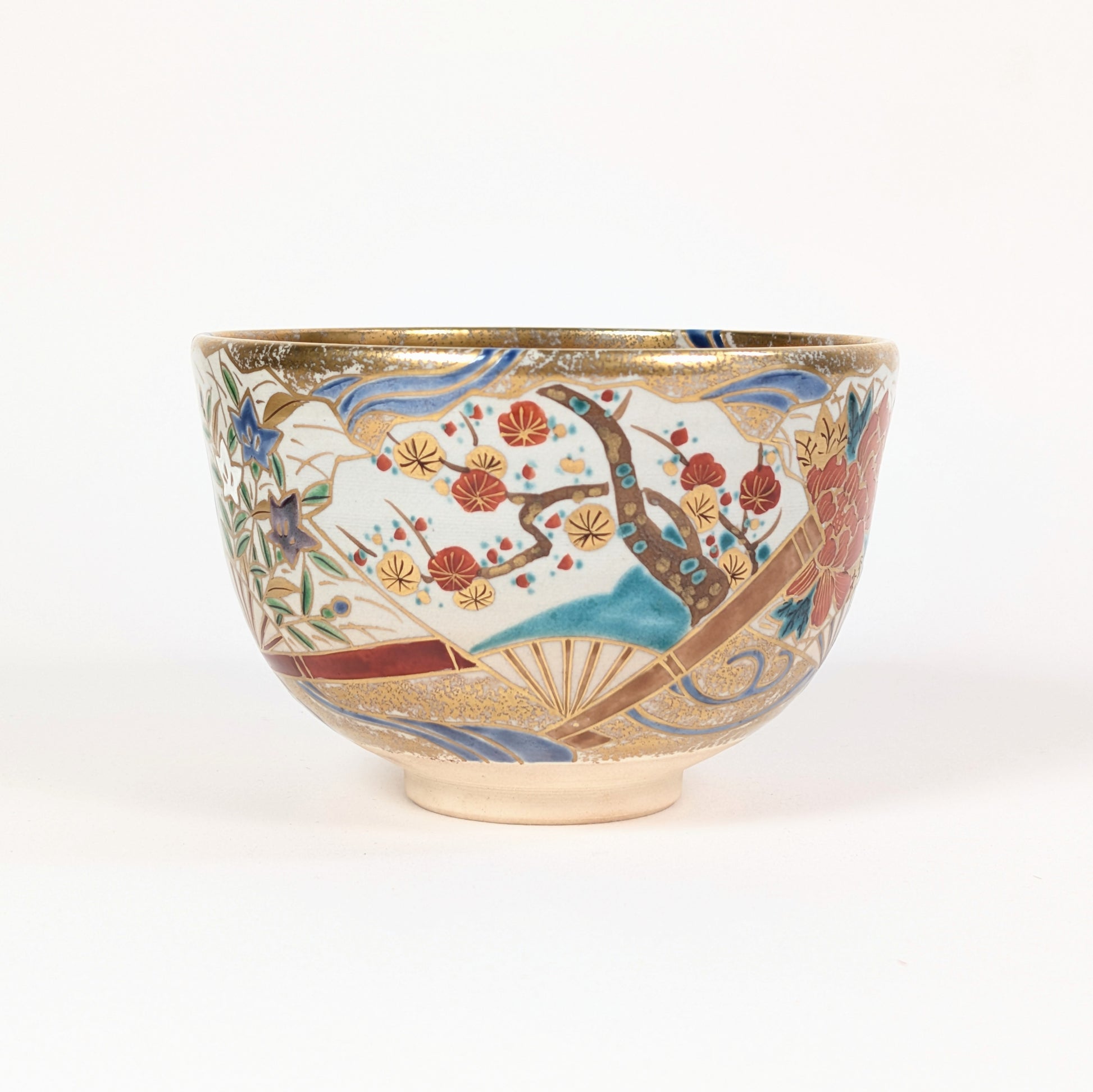Profil du chawan de forme komogai-nari, orné d’une branche de prunier ume, d’éventails flottants et de vagues stylisées.