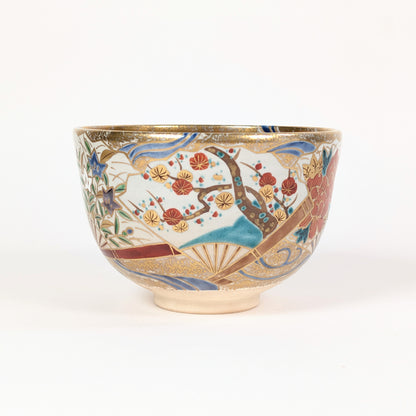 Profil du chawan de forme komogai-nari, orné d’une branche de prunier ume, d’éventails flottants et de vagues stylisées.