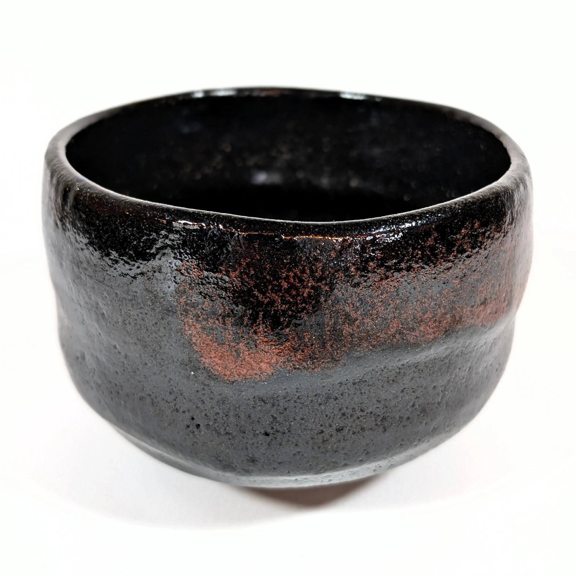 Bol à thé japonais en raku noir, œuvre artisanale de Sasaki Shoraku, photographié en vue oblique pour révéler les nuances de la glaçure.