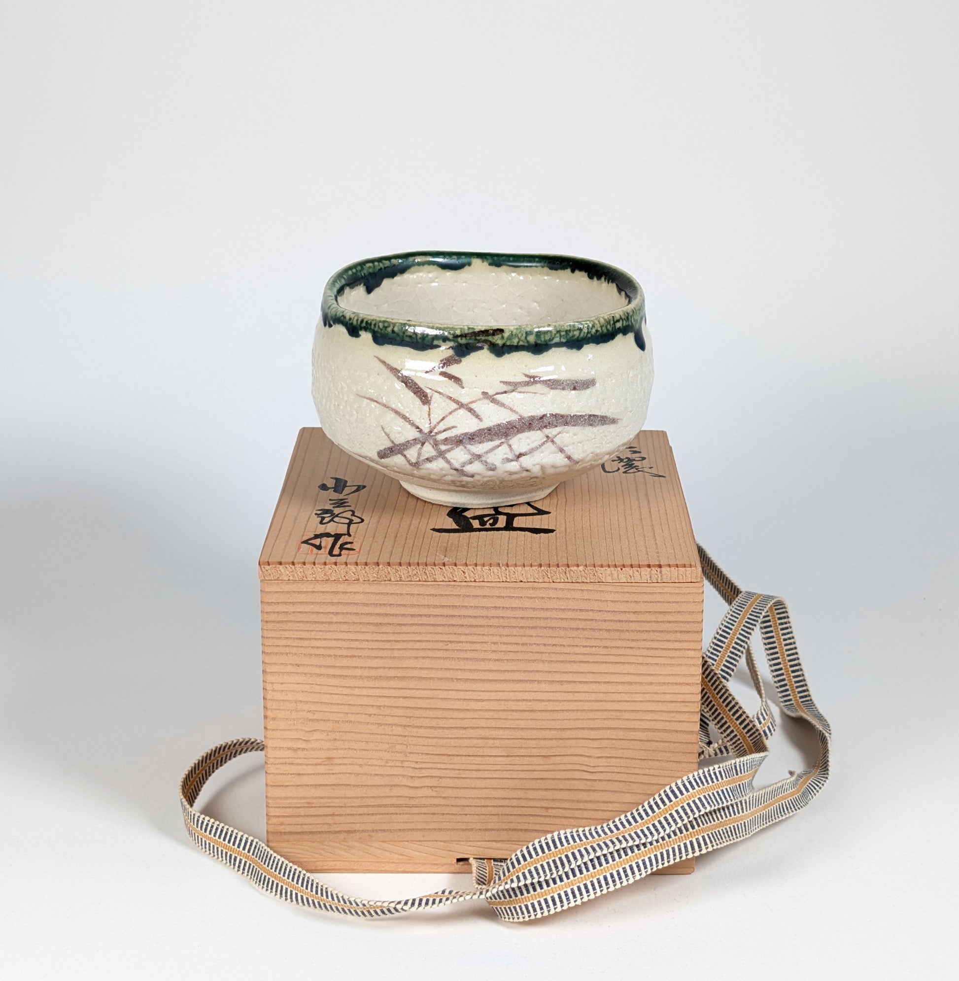 Chawan Oribe posé sur son tomobako, boîte en bois signée de l’atelier Kikyōya-gama avec cordon sanada-himo