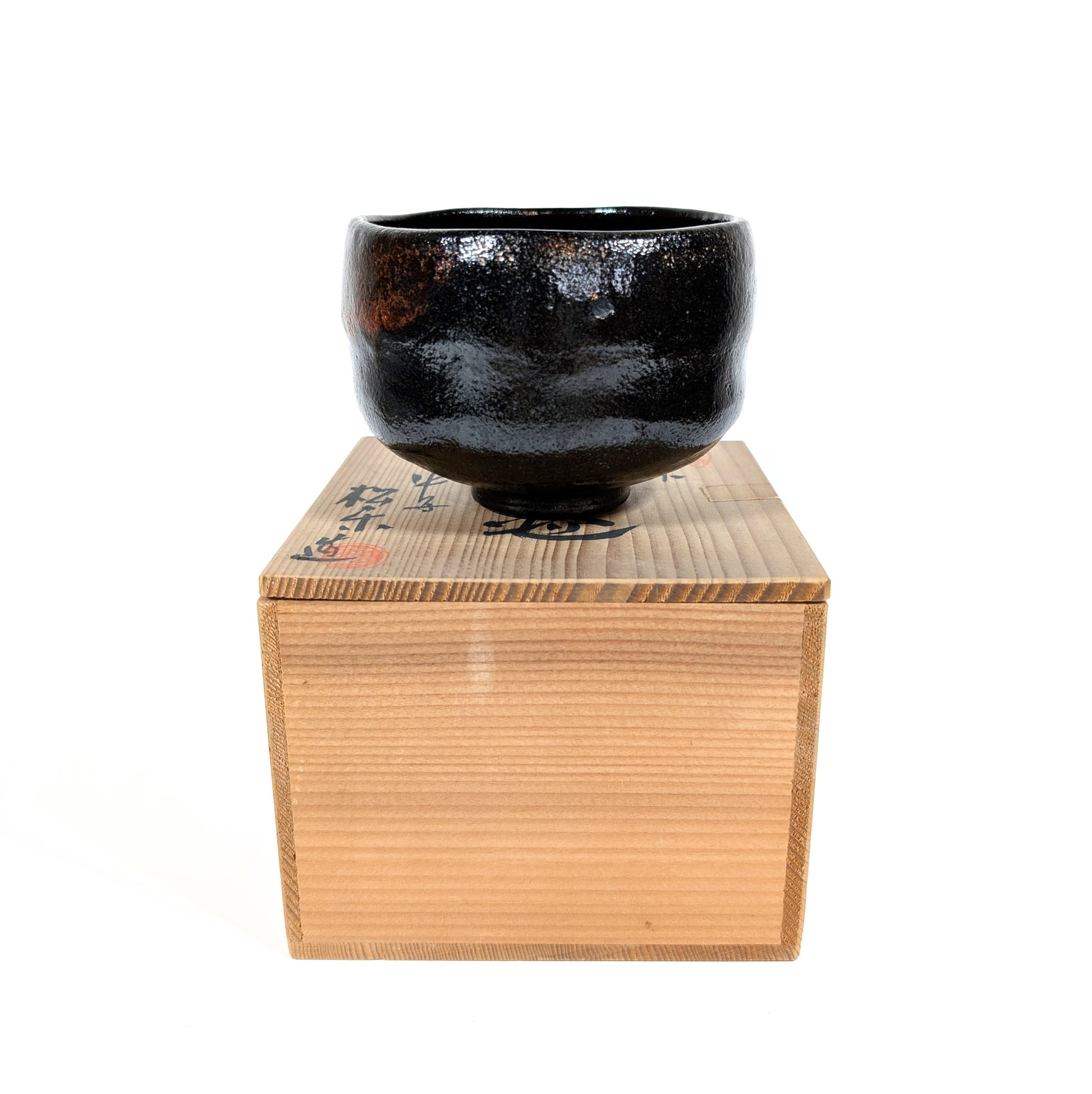 Chawan en raku noir fabriqué par Sasaki Shoraku, présenté sur sa boîte tomobako en bois.