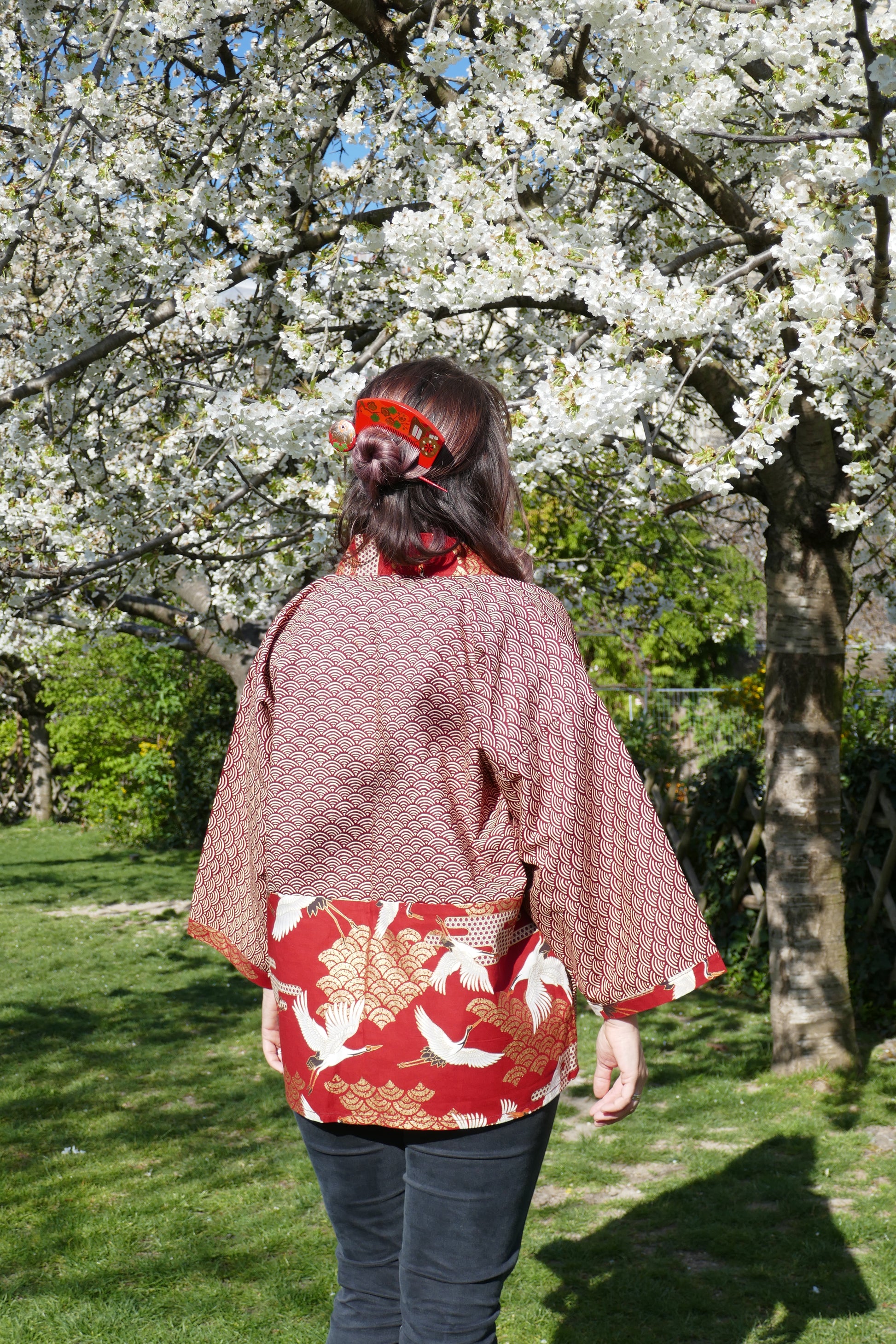 mikan est de dos, elle porte le haori akane tsuru kushi avec un kushi et un kanzashi rouge kogedo 