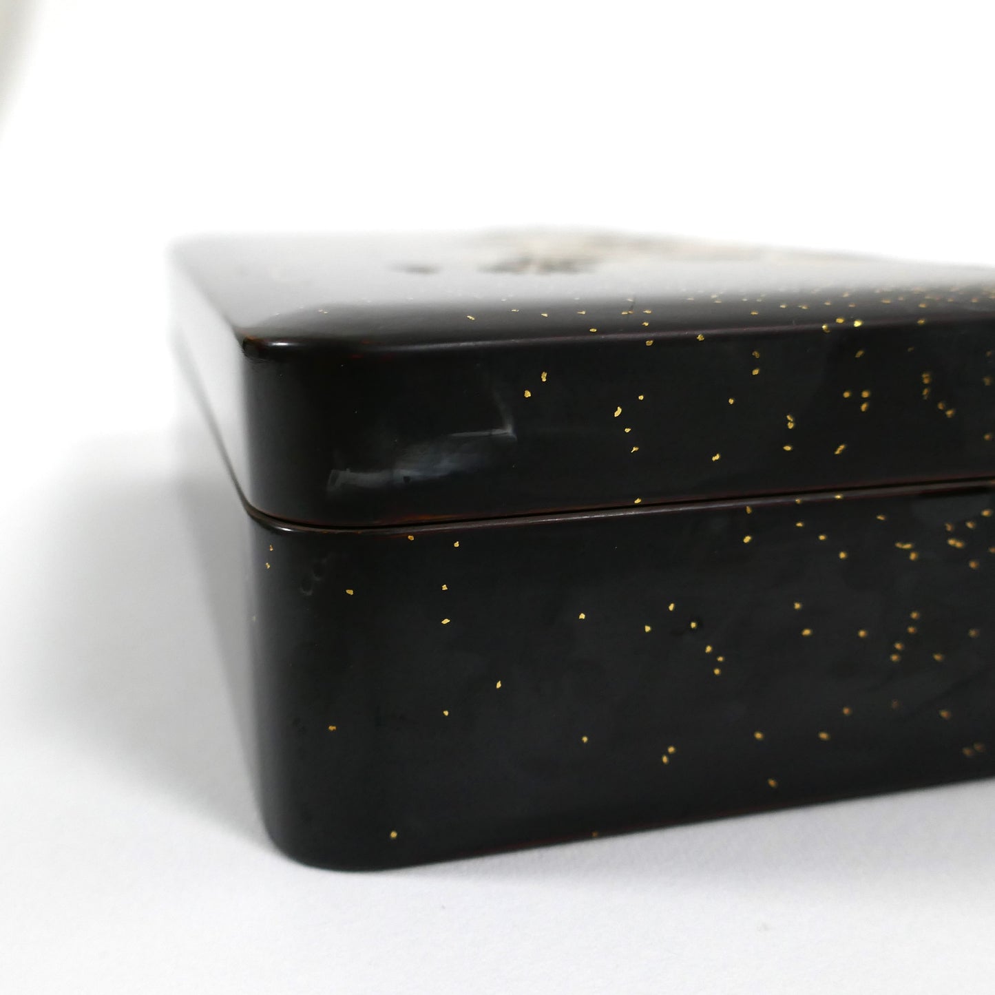 Détail du coin de la boîte en laque noire japonaise, finition brillante avec éclats de poudre d’or.
