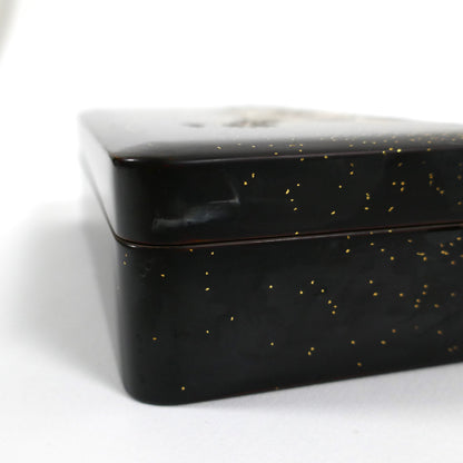 Détail du coin de la boîte en laque noire japonaise, finition brillante avec éclats de poudre d’or.