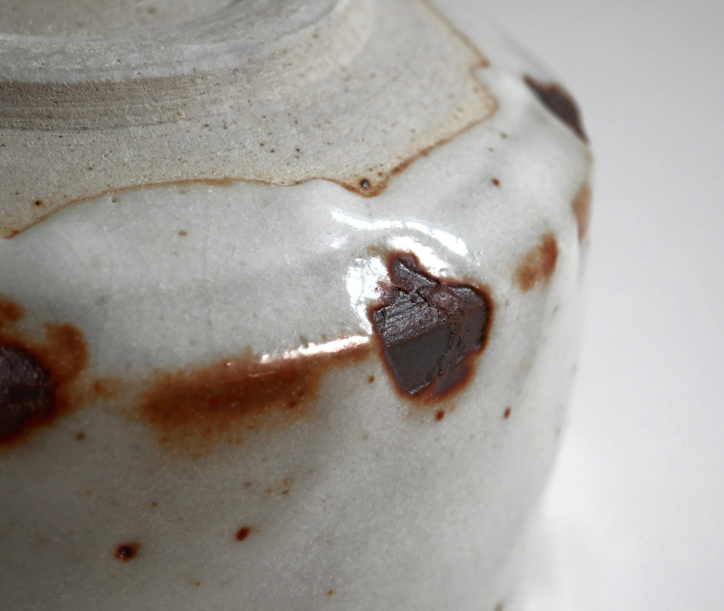 Détail de coulure d’émail Beni Shino près du pied du chawan, contraste blanc et brun rouille dans l’esprit wabi sabi japonais.
