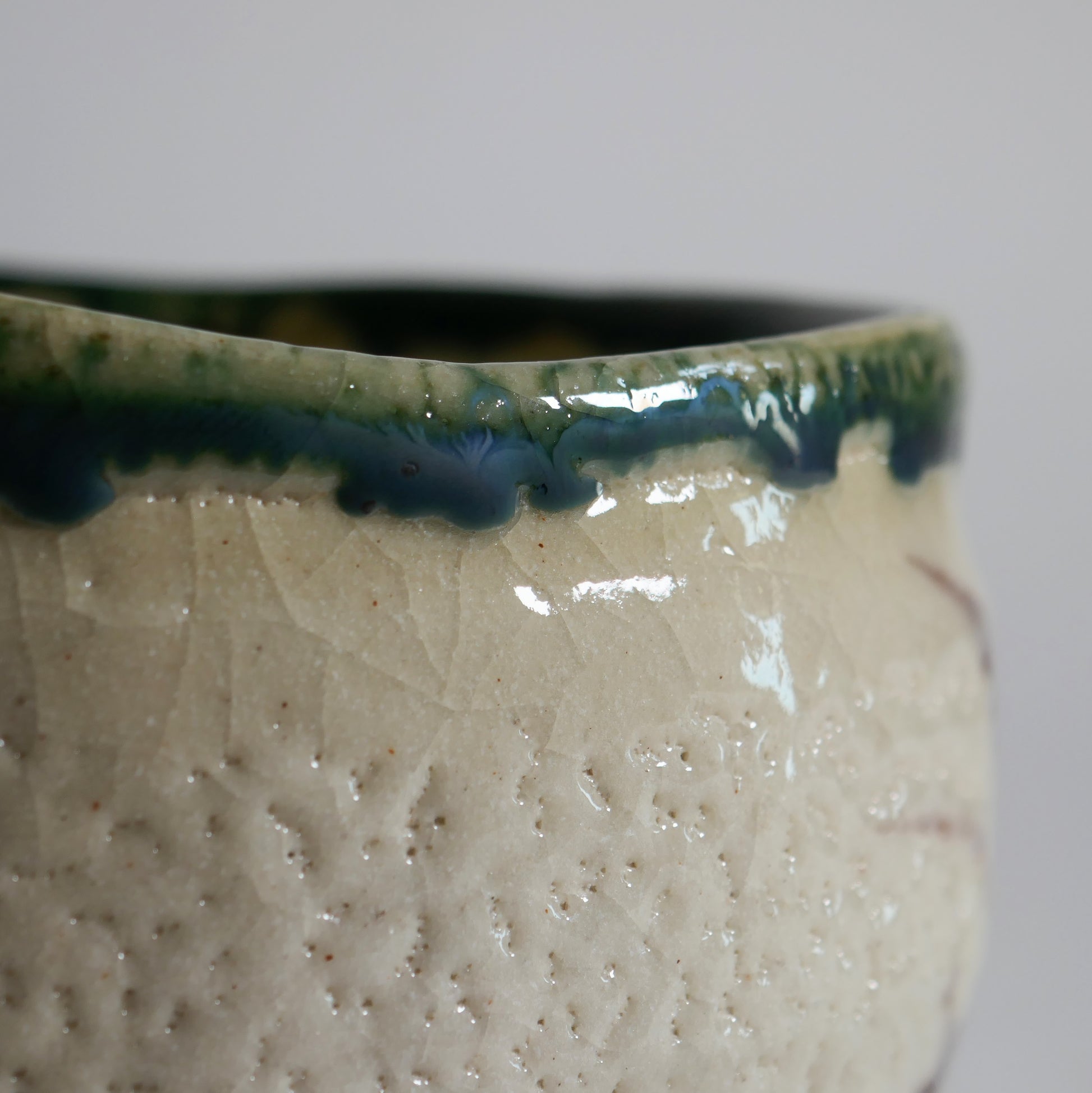 Gros plan sur les coulures de glaçure verte Oribe et la texture craquelée d’un chawan japonais en céramique