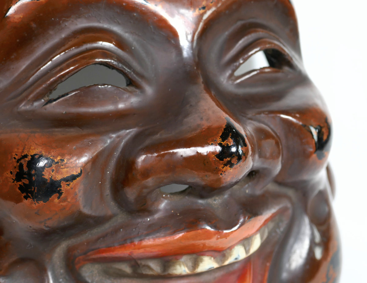 Détail du visage souriant d’un Daikoku-men 大黒面 en laque sèche kanshitsu, masque japonais traditionnel de divinité de la prospérité.