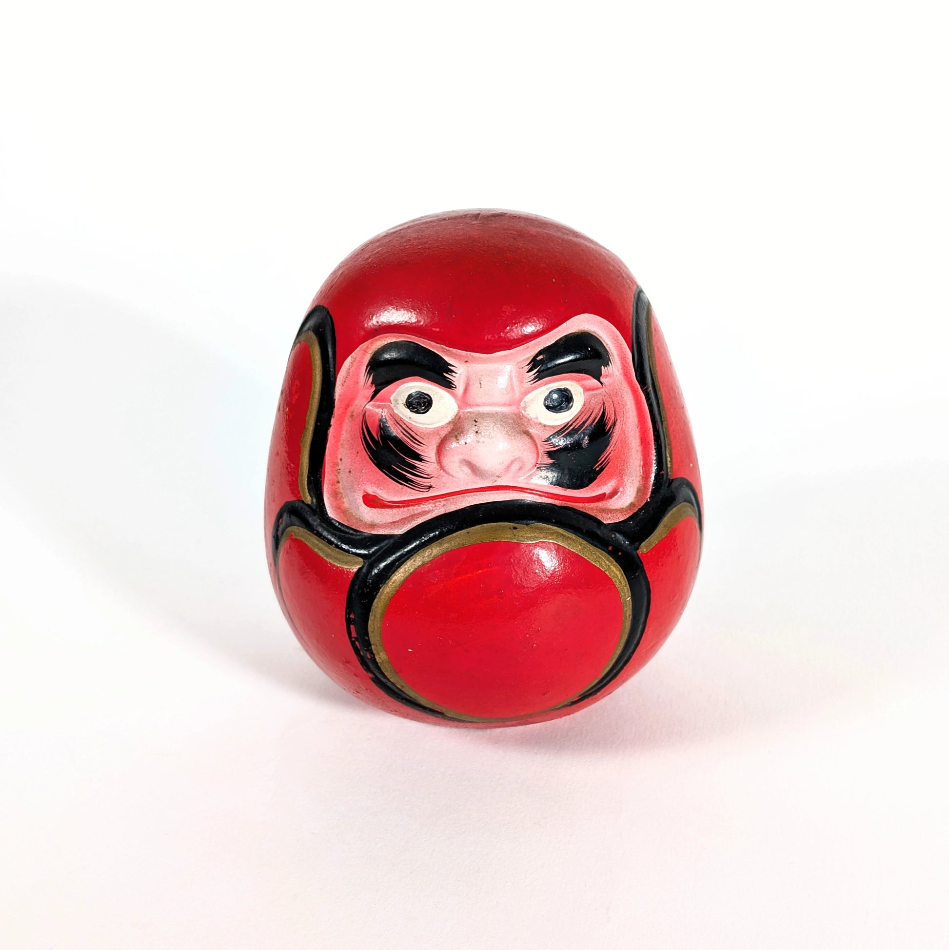 Daruma japonais vintage en céramique rouge, vu de face, avec expression traditionnelle