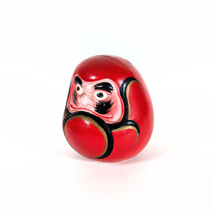 Vue de profil d’un daruma japonais vintage en céramique rouge