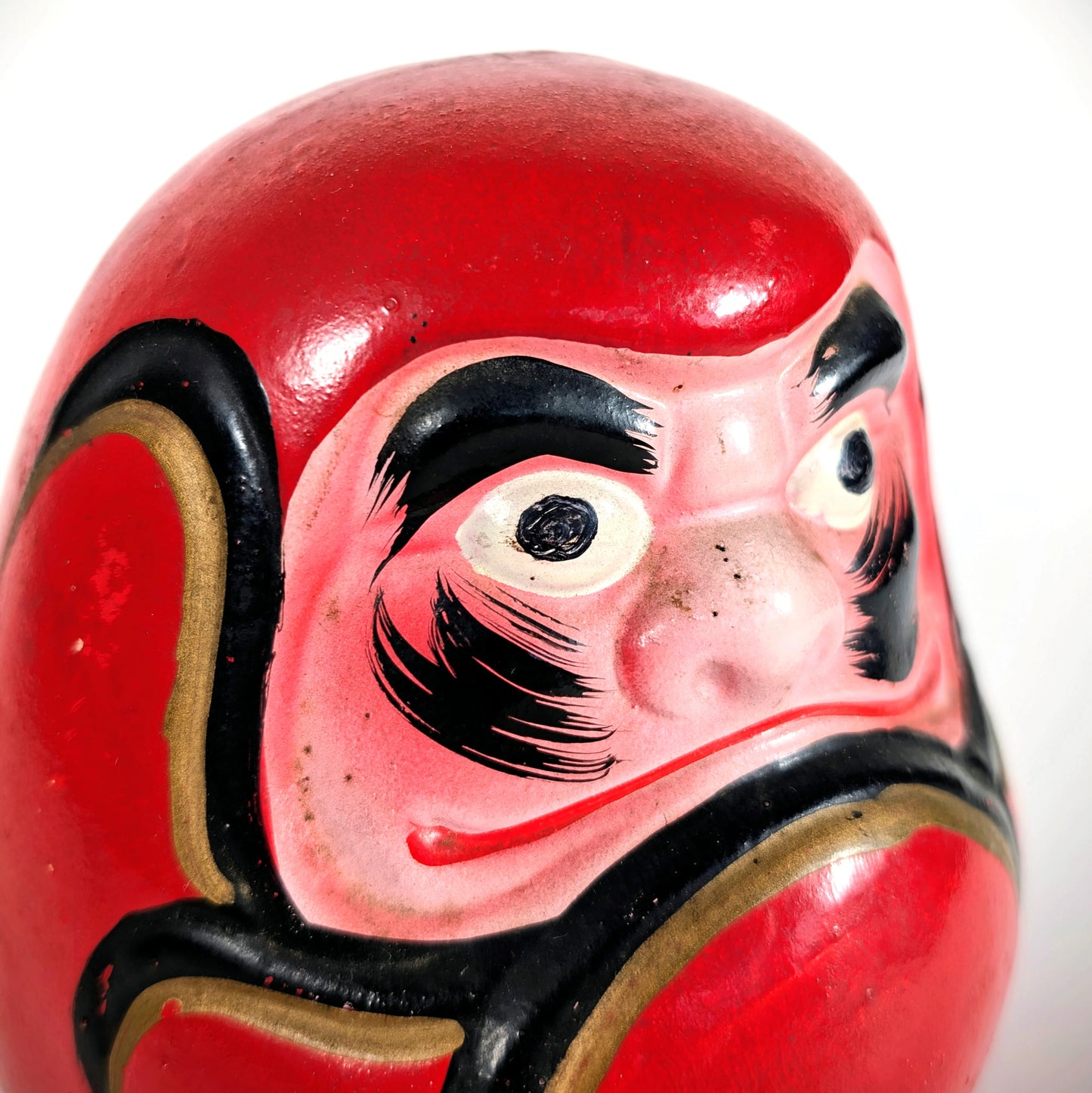 Détail du visage peint à la main d’un daruma japonais vintage en céramique